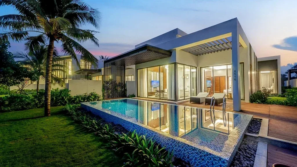 Villa 2 Phòng Ngủ – Hồ Bơi Riêng ở Vinpearl Resort & Golf Nam Hội An lúc chạng vạng, hồ bơi dài trước phòng khách kính
