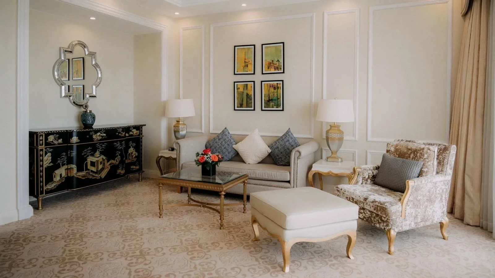 Phòng khách riêng trong hạng Deluxe Suite Ocean View của Wyndham Grand Phu Quoc với sofa kem, bàn trà mặt kính và tủ sơn mài