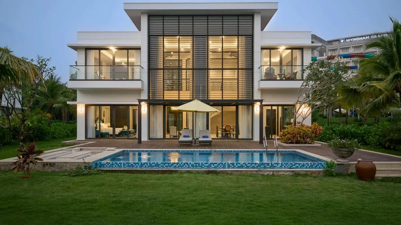 Villa hai tầng có hồ bơi riêng và bãi cỏ phía trước tại Wyndham Grand Phu Quoc, biển hiệu khách sạn phía sau